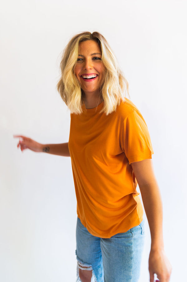 the “fancier” version of a t-shirt. the design: blank for all of our ladies who love a good basic tee! color: apricot buff tee. the material:100% viscose with a boxy, slouchy fit. the sleeves are wide with a ringer style neckline. HIGH CHANCE OF SHRINKAGE! Wash on cold and then hang dry! It will shrink in length in the dryer. Ramble &amp; Co. is a family lifestyle brand creating simple, timeless, quality apparel. Each piece is handprinted in our brick and mortar studio located in Wichita Falls, Texas.  