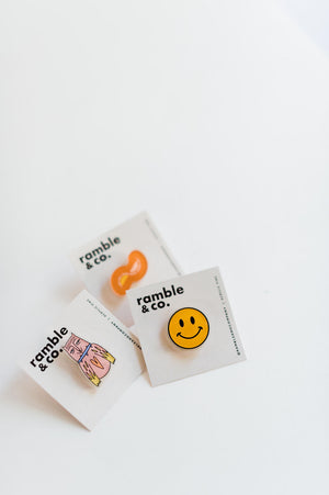 the design: yellow smile approx. 1 x 1 inches acrylic material  attach this button to a jacket, backpack, or wherever you go!   Ramble & Co. is a family owned business. Shop at shop.rambleandcompany.com or visit our store in Wichita Falls, Texas || small batch/ hand printed tees + fine art prints | your source of encouragement + inspiration.