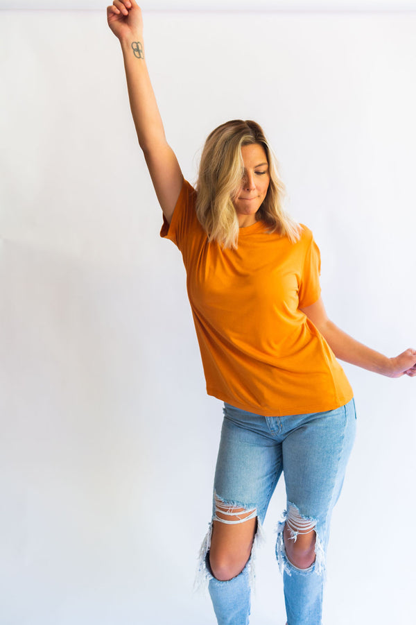 the “fancier” version of a t-shirt. the design: blank for all of our ladies who love a good basic tee! color: apricot buff tee. the material:100% viscose with a boxy, slouchy fit. the sleeves are wide with a ringer style neckline. HIGH CHANCE OF SHRINKAGE! Wash on cold and then hang dry! It will shrink in length in the dryer. Ramble &amp; Co. is a family lifestyle brand creating simple, timeless, quality apparel. Each piece is handprinted in our brick and mortar studio located in Wichita Falls, Texas.  