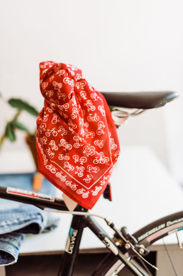 Red bandana with white bicycles design by Hemlock Goods | you can shop now at  shop.rambleandcompany.com or visit our storefront in downtown Wichita Falls, Texas || small batch + hand printed tees | home goods | paper goods | gifts + more