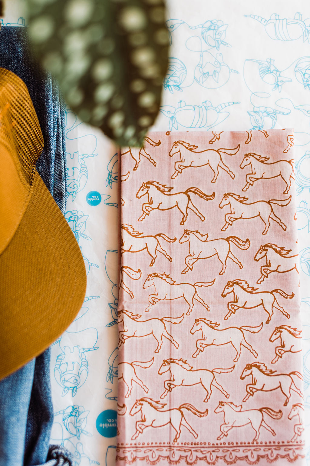 Pink bandana with brown outlined horses design by Hemlock Goods | you can shop now at  shop.rambleandcompany.com or visit our storefront in downtown Wichita Falls, Texas || small batch + hand printed tees | home goods | paper goods | gifts + more