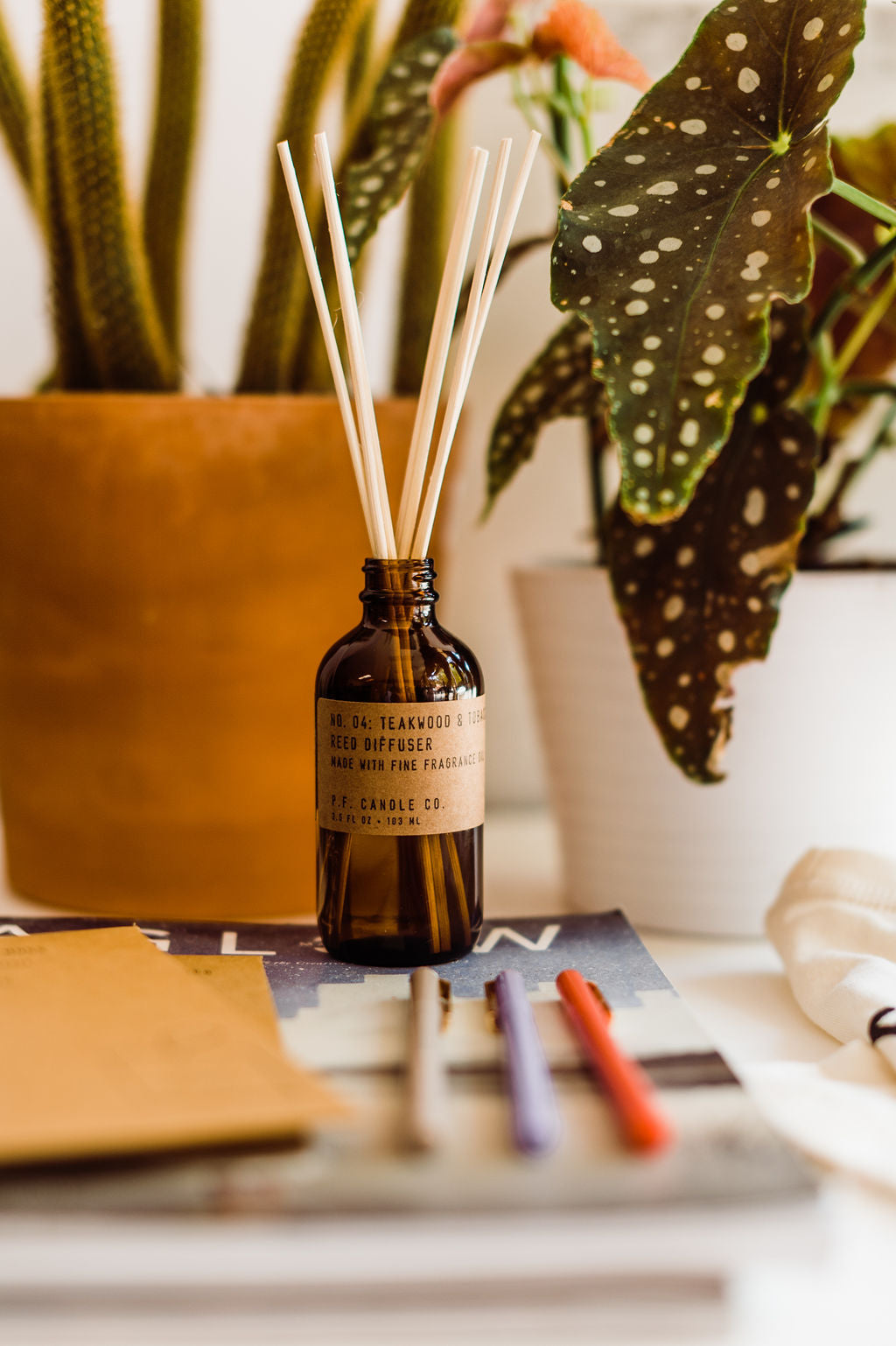 3.5 fl oz glass bottle reed diffuser that includes rattan reeds and made with naturally-derived and man-made fragrance oils | scent is a  blend of leather, teak, and orange | made by PF Candle Co. || you can shop now at shop.rambleandcompany.com or visit our storefront in downtown Wichita Falls, Texas || small batch + hand printed tees | home goods | paper goods | gifts + more