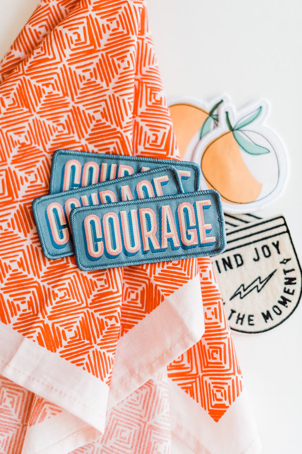 Iron on, blue patch with Courage written in bold pink letters by Ramble & Company  | you can shop now at  shop.rambleandcompany.com or visit our storefront in downtown Wichita Falls, Texas || small batch + hand printed tees | home goods | paper goods | gifts + more