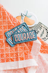 Iron on, blue patch with Courage written in bold pink letters by Ramble & Company  | you can shop now at  shop.rambleandcompany.com or visit our storefront in downtown Wichita Falls, Texas || small batch + hand printed tees | home goods | paper goods | gifts + more