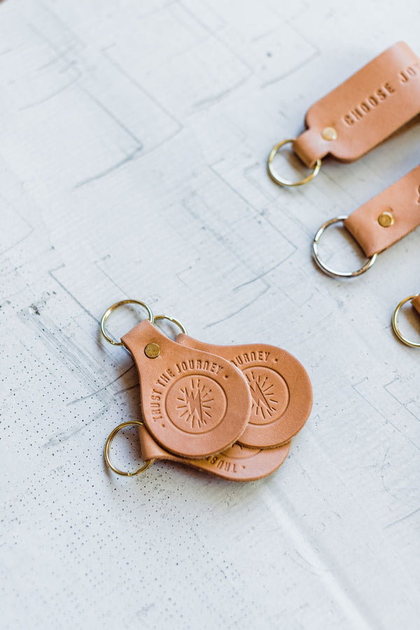 the design: trust the journey. the material: leather. hand stamped by lost penguin leather, made in texas. key fobs are fun but leather key fobs are the most fun. Ramble &amp; Co. is a family owned business. Shop at shop.rambleandcompany.com or visit our store in Wichita Falls, Texas || small batch/ hand printed tees + fine art prints | your source of encouragement + inspiration.
